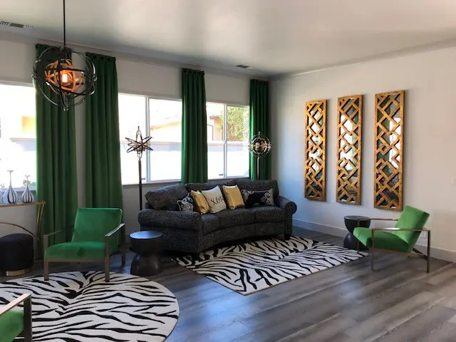 A living room with green curtains and zebra print rugs.