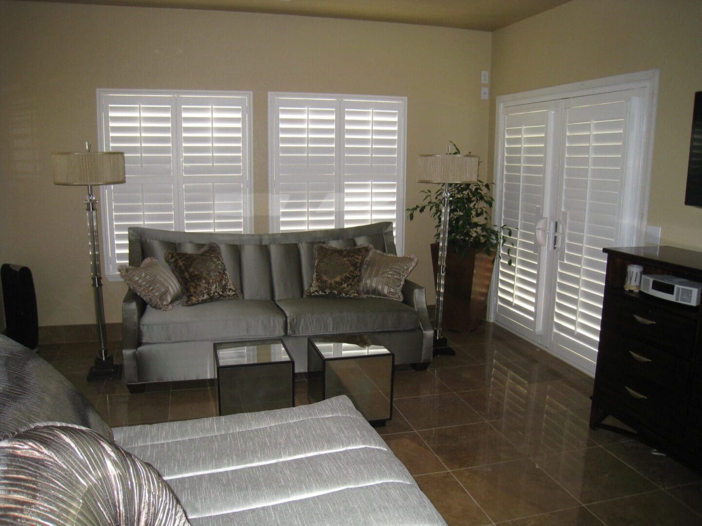 A living room with white shutters and a couch