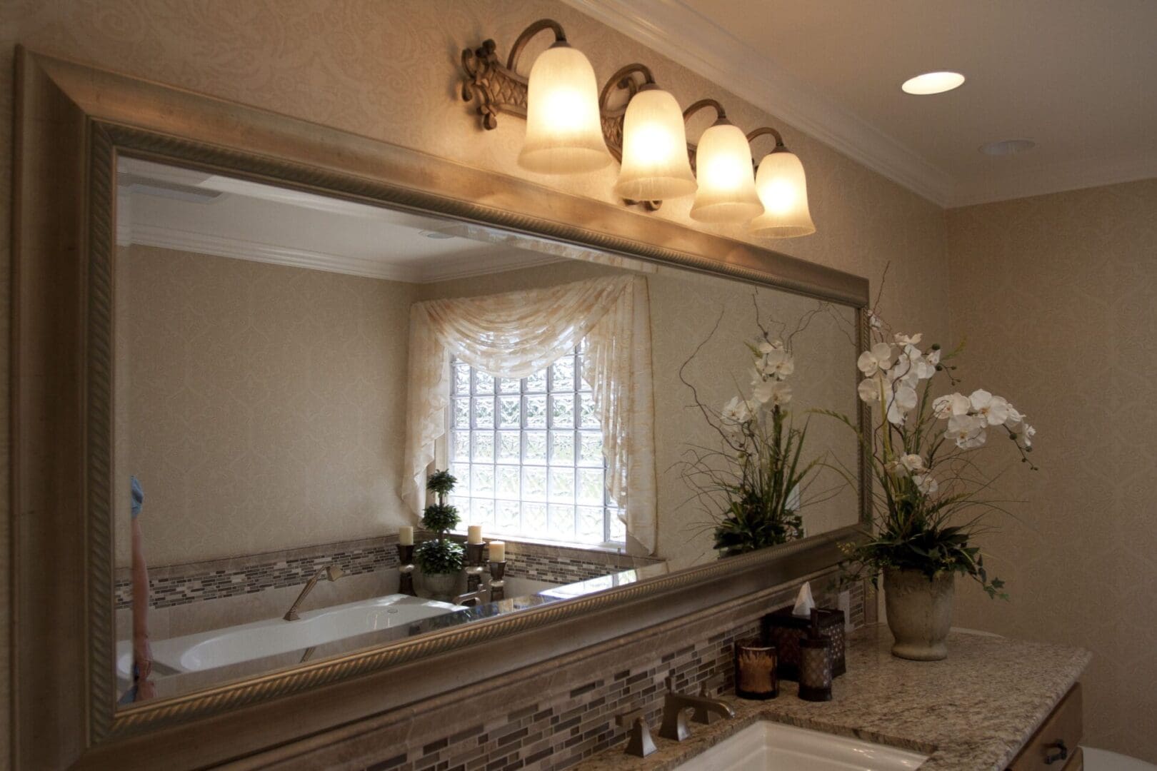 A bathroom with a large mirror and lights above the sink.
